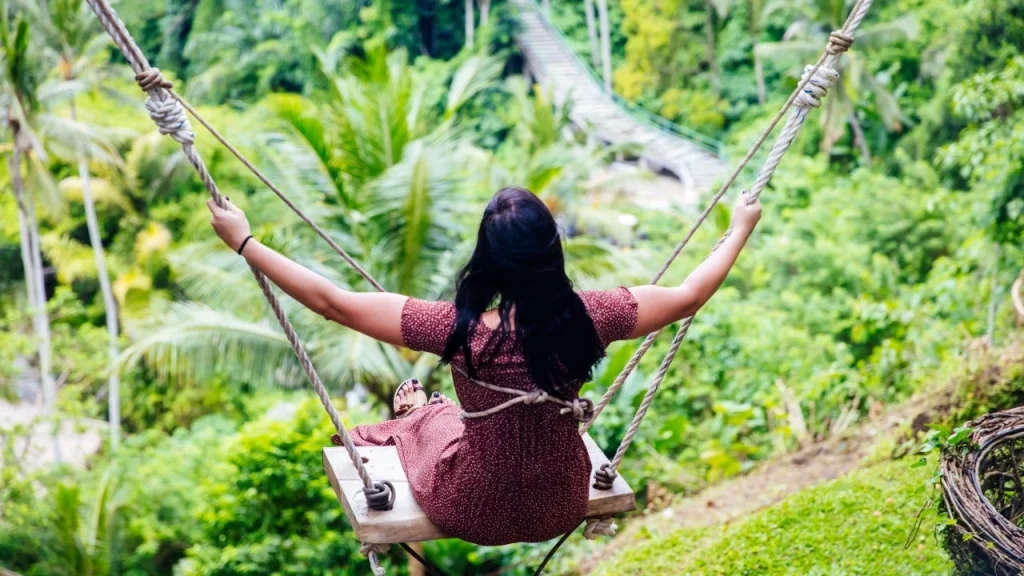 Traveler enjoying giant swing overlooking rice terraces and jungle in Ubud